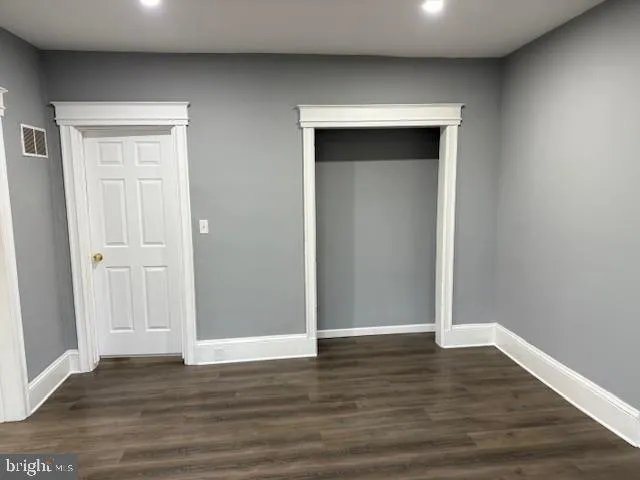 a view of an empty room with wooden floor & closet