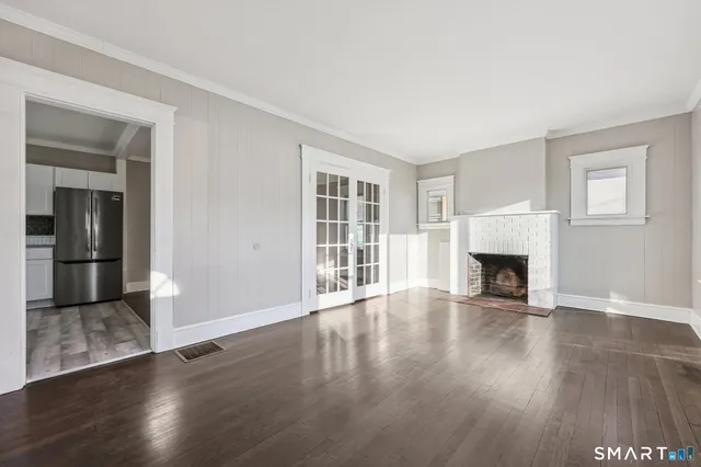 an empty room with wooden floor fireplace and windows
