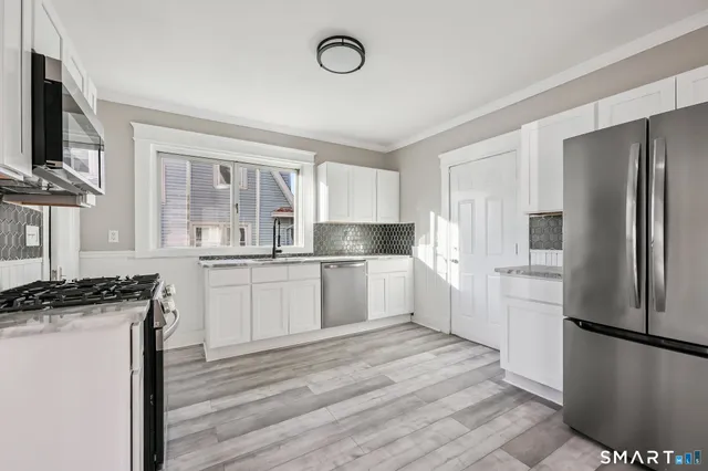 a kitchen with a refrigerator a stove top oven and white cabinets
