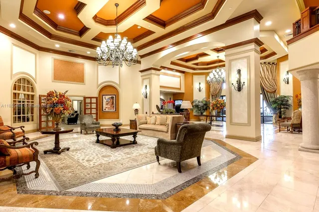 a living room with couches a chandelier and a dining table with a large window