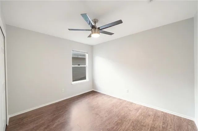 an empty room with a window and ceiling fan