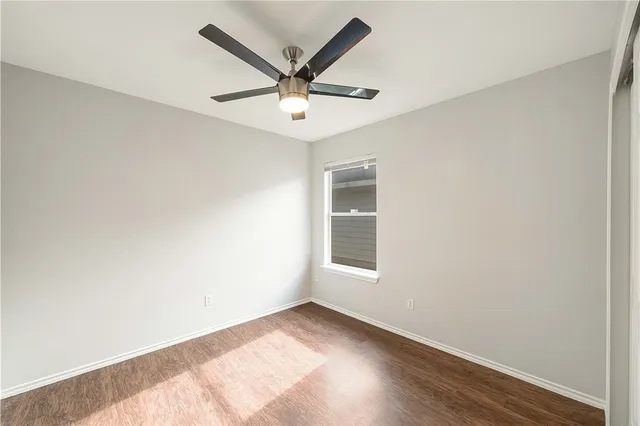 an empty room with a window and ceiling fan