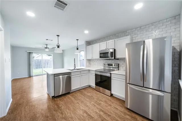 a kitchen with stainless steel appliances granite countertop a refrigerator a stove a sink dishwasher a microwave oven with cabinets and wooden floor