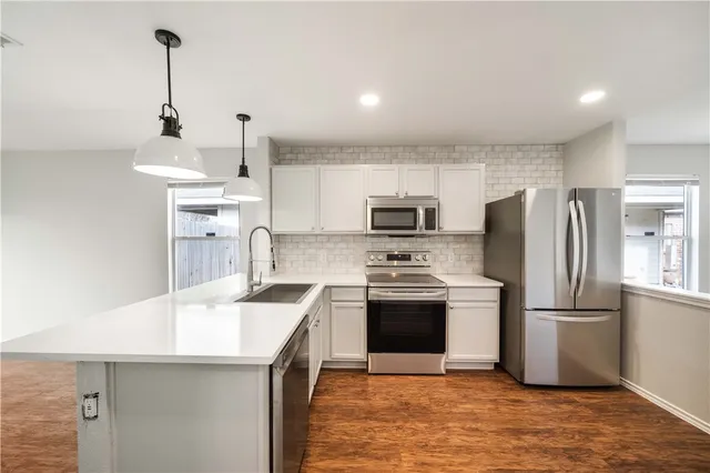 a kitchen with stainless steel appliances a sink stove refrigerator and cabinets