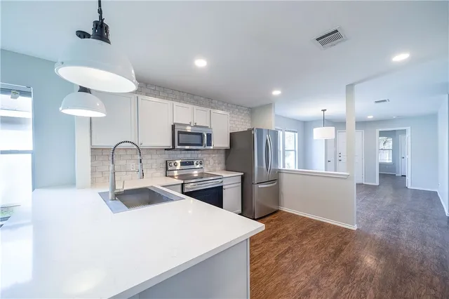 a large kitchen with stainless steel appliances kitchen island a stove a sink a refrigerator and a microwave