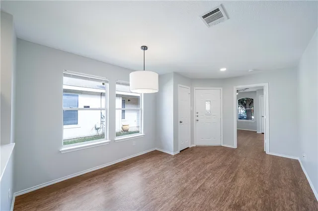 a view of an empty room with a window and wooden floor