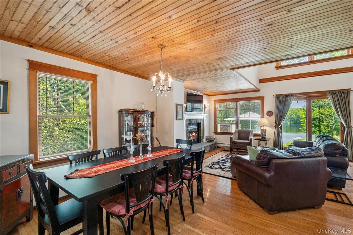 342 Lake Shore Road Putnam Valley, NY 10579 - Photo 9 of 46 Dining space featuring a warm lit fireplace, wood ceiling, light wood-type flooring, a chandelier, and ornamental molding