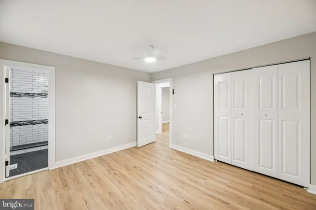 a view of empty room with wooden floor and fan