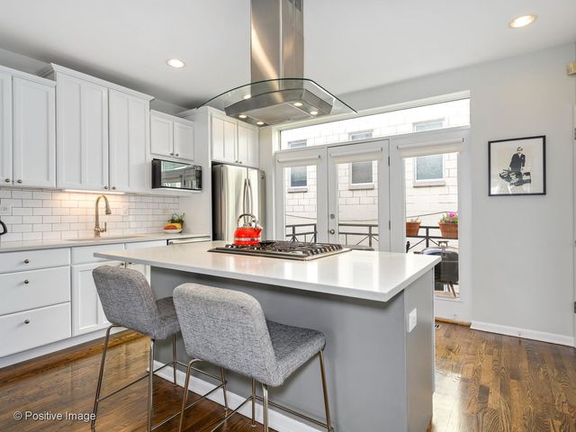 a kitchen with stainless steel appliances granite countertop a dining table chairs sink and cabinets