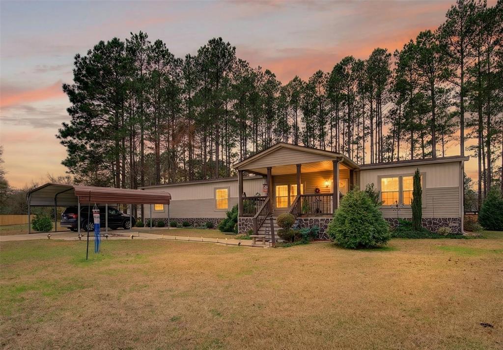 View of front of home with a front lawn, a porch, and a detached carport