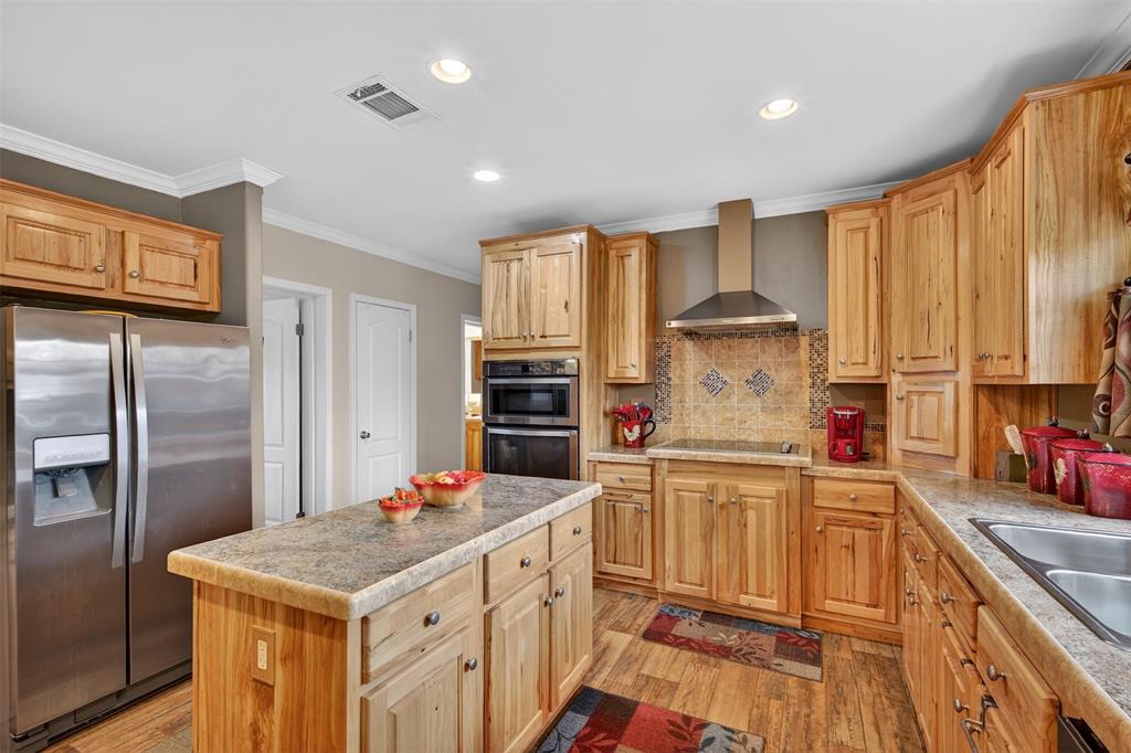 8794 Castle Dale Loop Shreveport, LA 71107 - Photo 13 of 31 Kitchen with stainless steel appliances, light countertops, a kitchen island, wall chimney exhaust hood, and ornamental molding