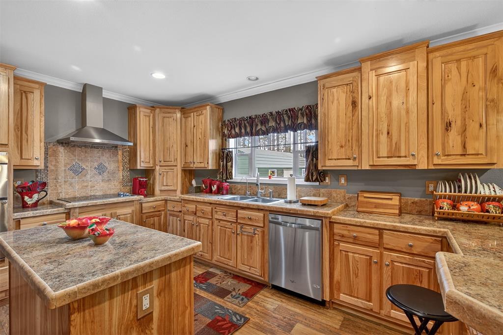 8794 Castle Dale Loop Shreveport, LA 71107 - Photo 14 of 31 Kitchen with stainless steel dishwasher, wall chimney range hood, light wood-style floors, recessed lighting, and a center island