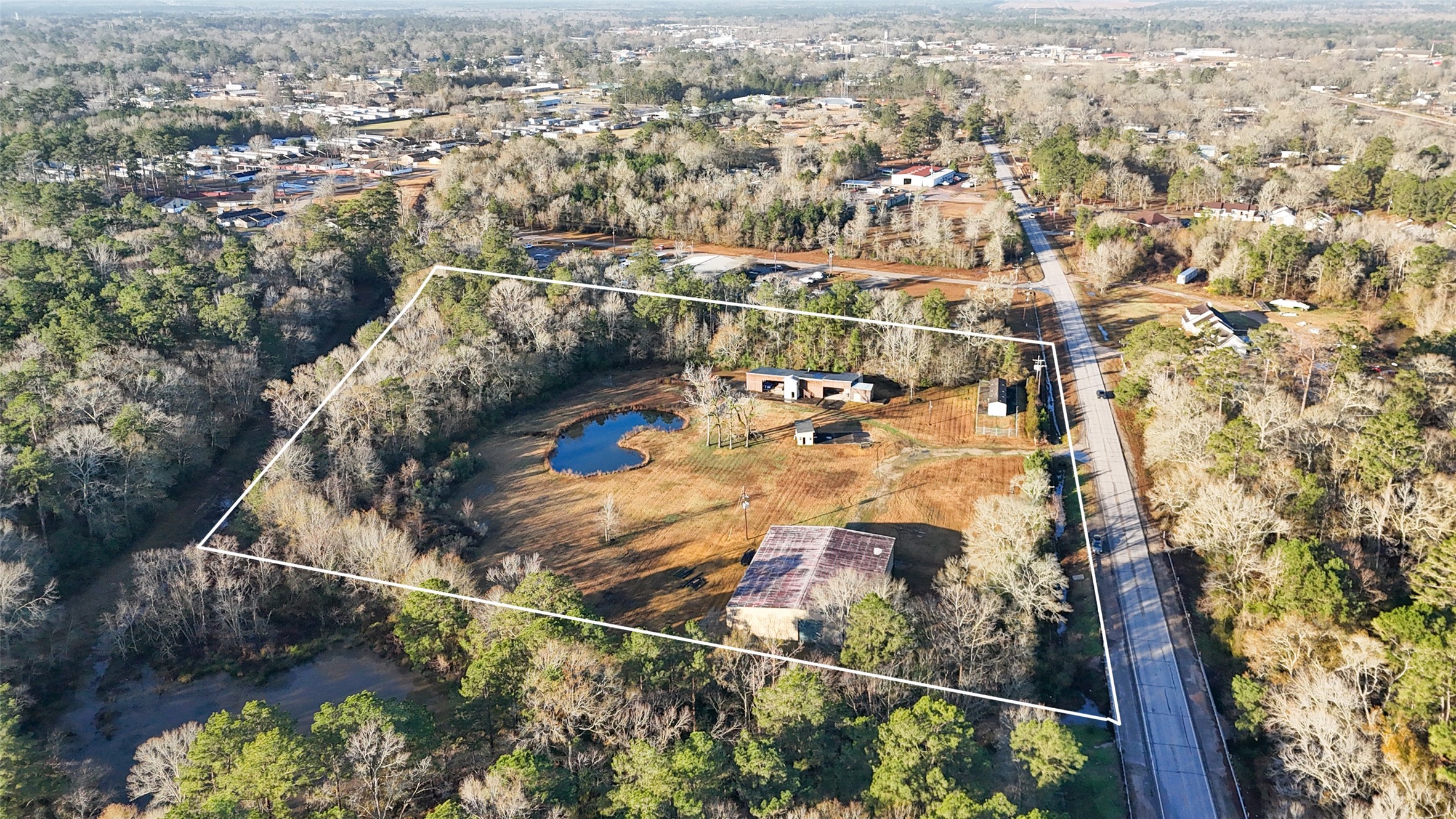 21405 Farm To Market 787 Cleveland, TX 77327 - Photo 8 of 24 Expansive rural property with a pond, surrounded by trees. Includes multiple buildings and open space, offering privacy and potential for development. Accessible via FM 787 with lots of road frontage.,