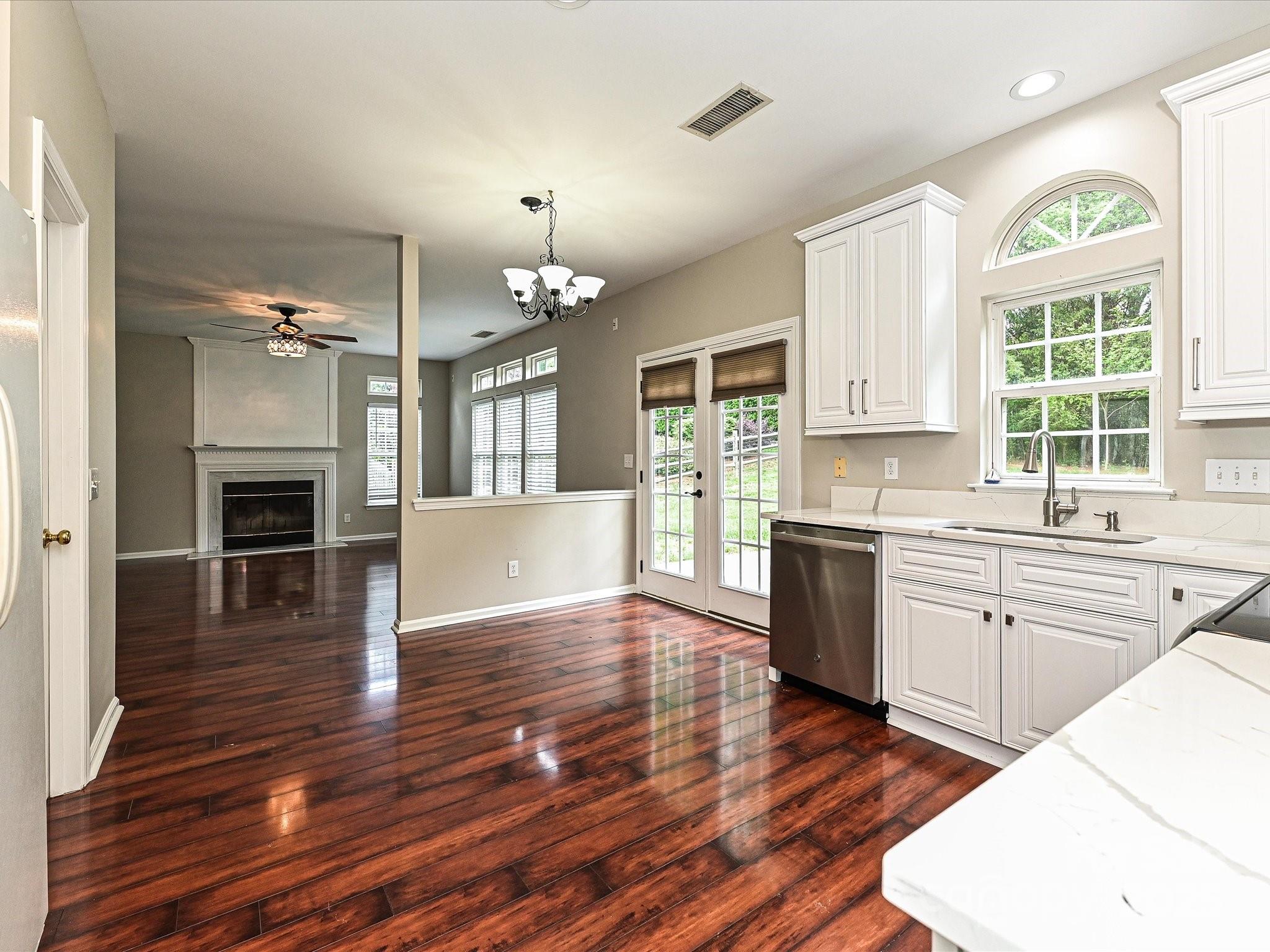 13237 Fremington Road Huntersville, NC 28078 - Photo 18 of 36 a open kitchen with granite countertop a stove top oven a sink dishwasher a refrigerator and white cabinets with wooden floor