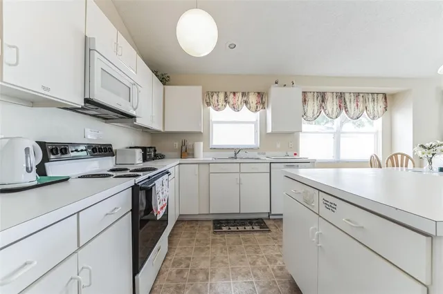 a kitchen with granite countertop white cabinets and white appliances