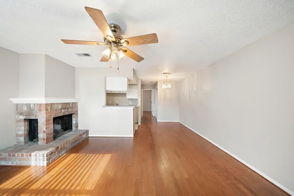a view of a livingroom with a fireplace a ceiling fan and wooden floor