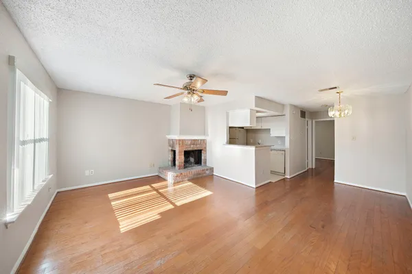 a living room with couches and kitchen view with wooden floor