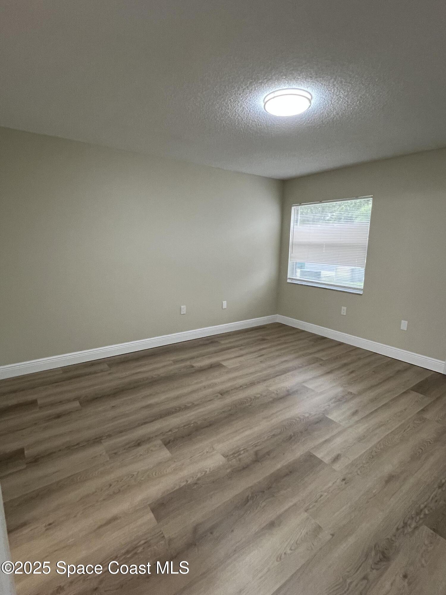 3154 Dunhill Drive Cocoa, FL 32926 - Photo 14 of 19 an empty room with wooden floor and windows