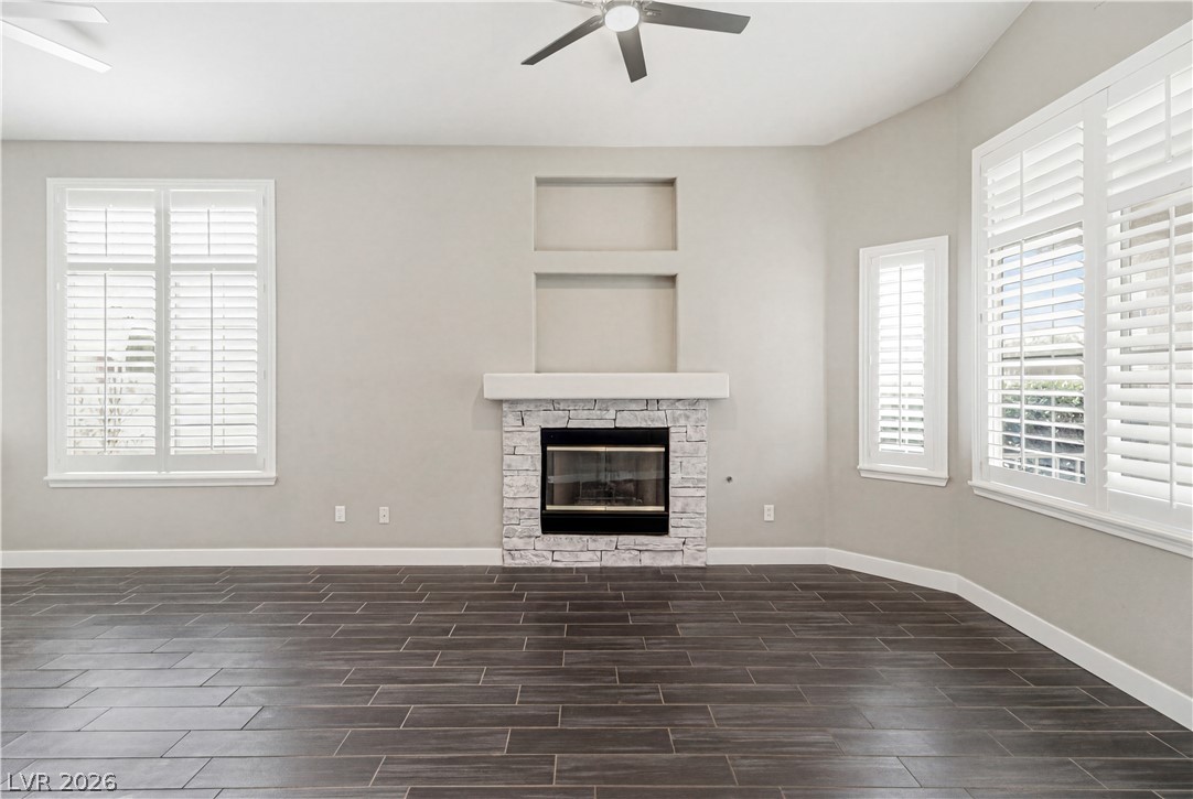 9523 Observer Street Las Vegas, NV 89123 - Photo 9 of 42 A well-lit living space features a stone fireplace with built-in wall niches, complemented by attractive wood-look tile flooring.