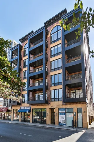 a front view of a building with lot of cars and trees