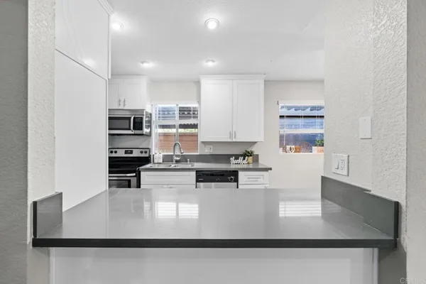 a kitchen with kitchen island granite countertop a stove top oven a sink a counter top space and cabinets