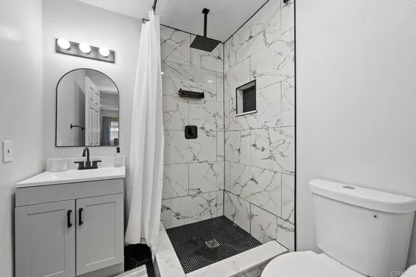 a bathroom with a sink a toilet a mirror and shower