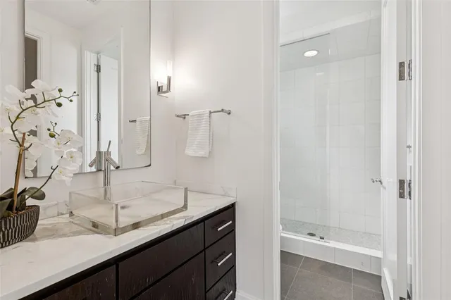 a bathroom with a granite countertop sink and a shower