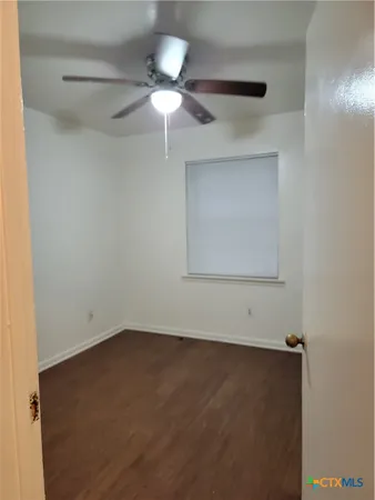 an empty room with a ceiling fan and a window
