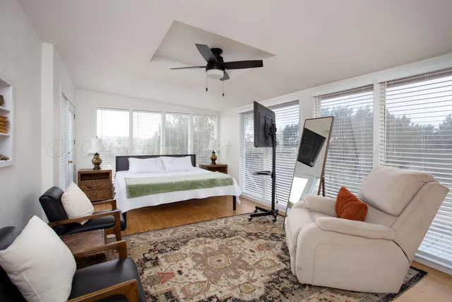 a bedroom with a bed a couch and large window