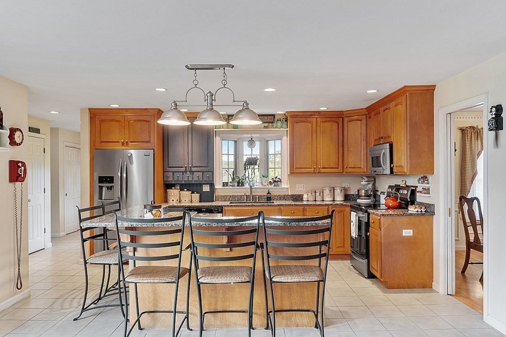 299 South Meadow Road Lancaster, MA 01523 - Photo 18 of 41 a dining hall with stainless steel appliances kitchen island granite countertop a dining table chairs and a refrigerator