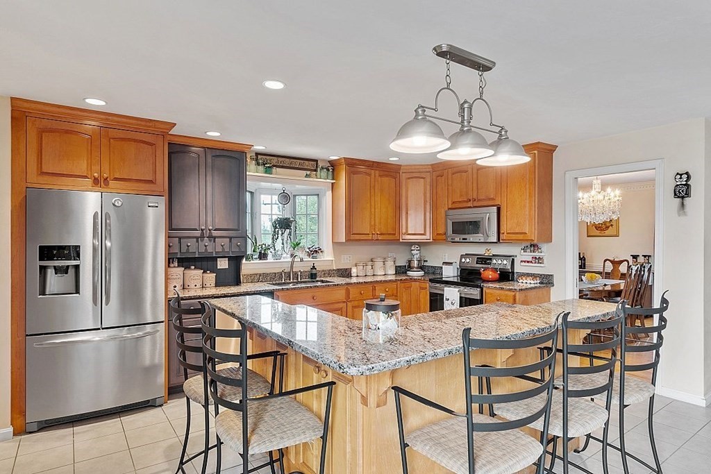 299 South Meadow Road Lancaster, MA 01523 - Photo 20 of 41 a kitchen with stainless steel appliances granite countertop a refrigerator a stove a sink a dining table and chairs with wooden floor