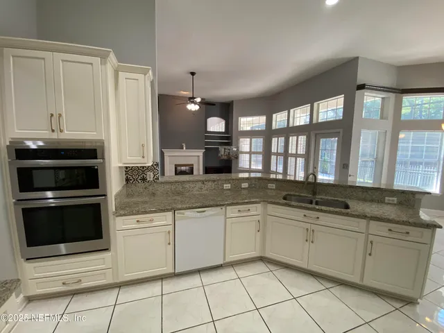 a kitchen with granite countertop a sink stainless steel appliances and white cabinets