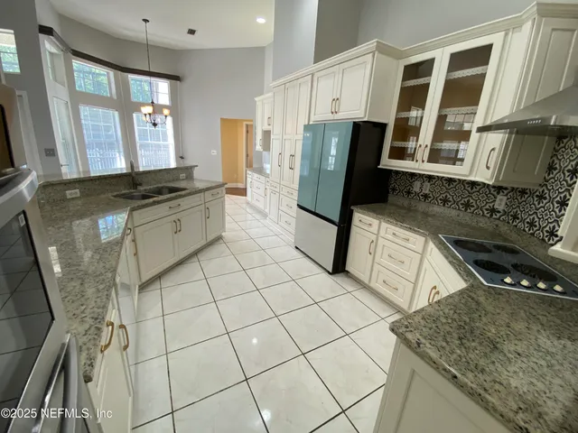 a kitchen with granite countertop a stove a sink and a refrigerator