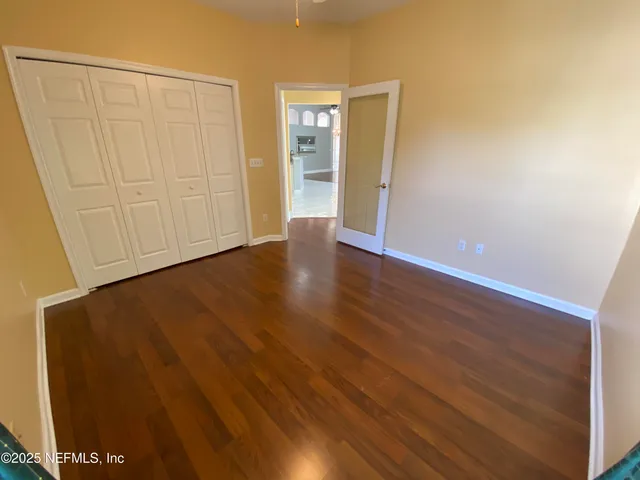a view of an empty room with wooden floor and closet