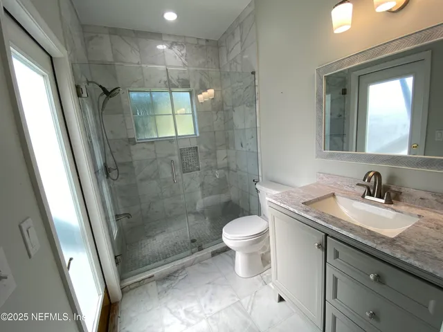 a bathroom with a granite countertop sink toilet and shower