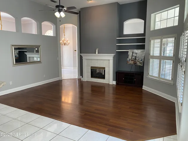 a view of a livingroom with furniture wooden floor fireplace and windows