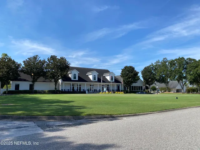 a view of a big house with a big yard and large trees
