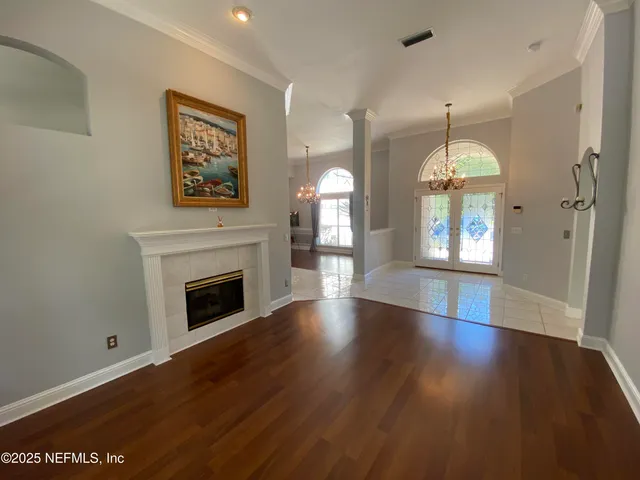 an empty room with wooden floor fireplace and windows