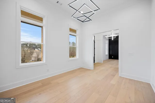 an empty room with chandelier fan and windows