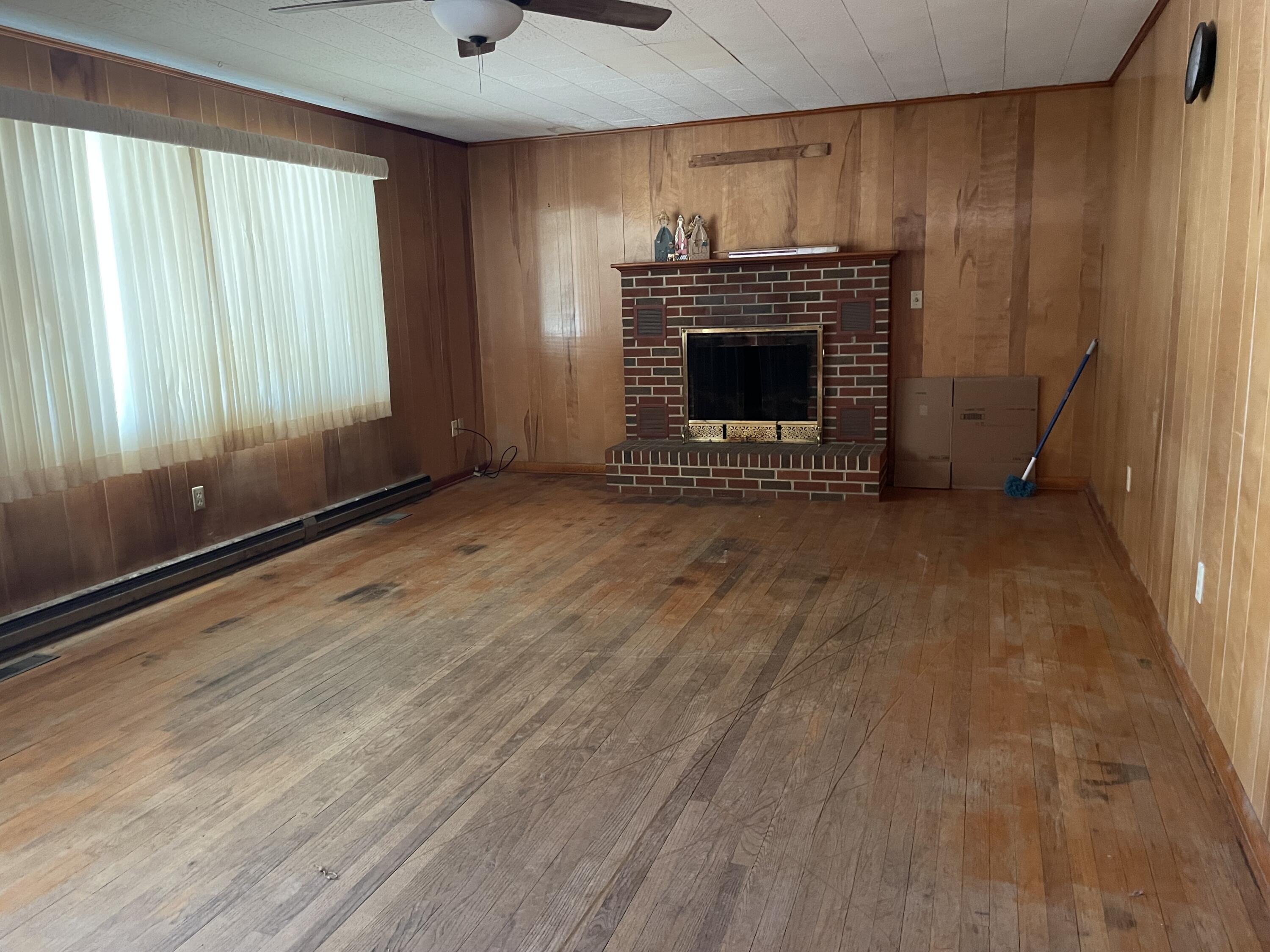 2047 Botetourt Road Fincastle, VA 24090 - Photo 4 of 11 an empty room with wooden floor fireplace and windows