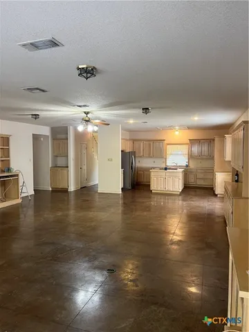 an empty room with chandelier fan and windows
