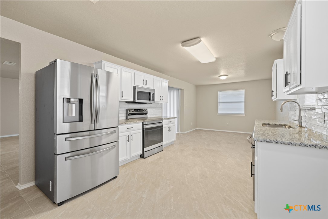 217 Timber Ridge Drive Nolanville, TX 76559 - Photo 11 of 25 a kitchen with stainless steel appliances granite countertop a refrigerator sink and stove