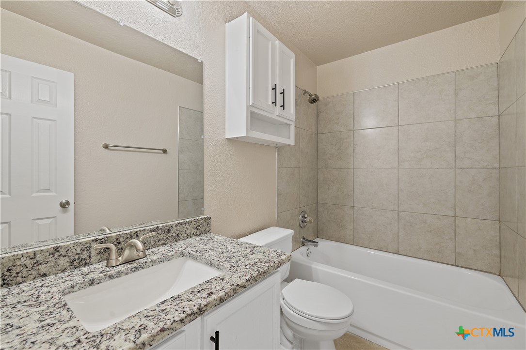 217 Timber Ridge Drive Nolanville, TX 76559 - Photo 18 of 25 a bathroom with a granite countertop sink a toilet and bathtub