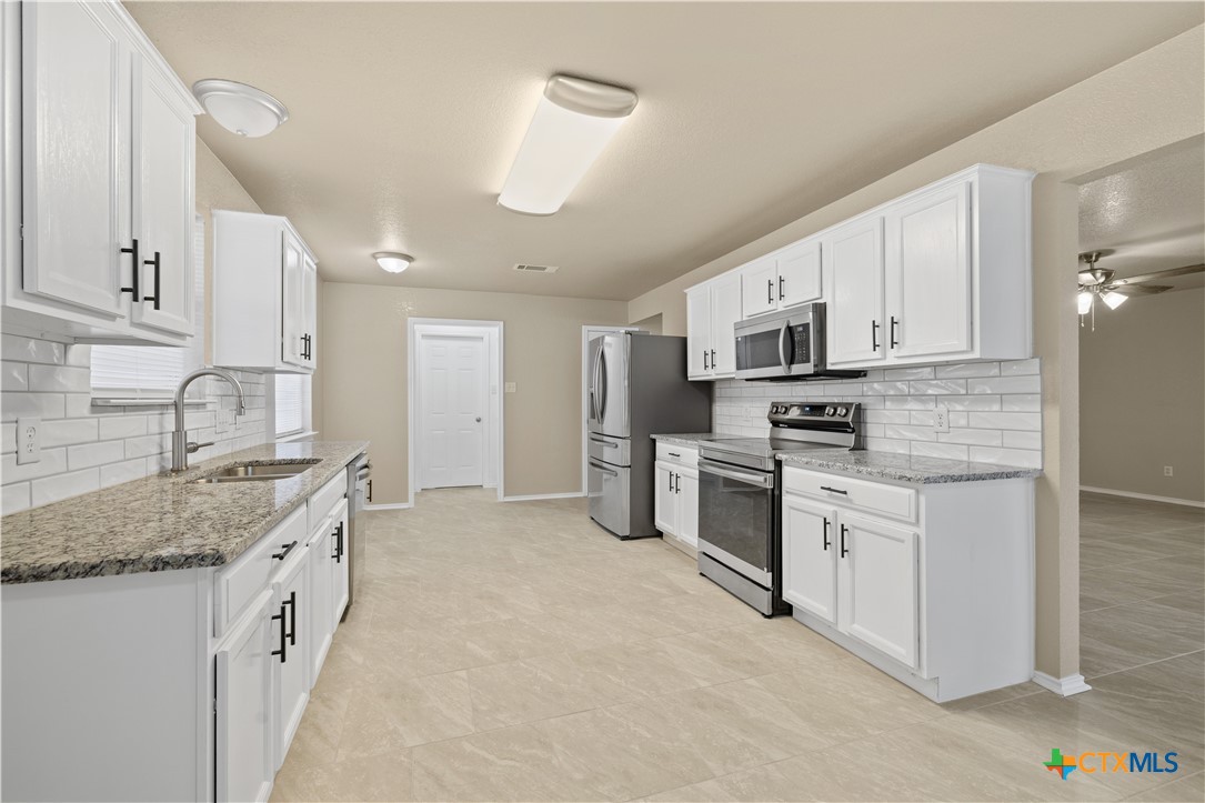 217 Timber Ridge Drive Nolanville, TX 76559 - Photo 10 of 25 a kitchen with granite countertop white cabinets and stainless steel appliances