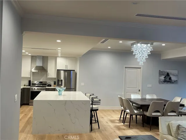 a living room with furniture a chandelier and kitchen view