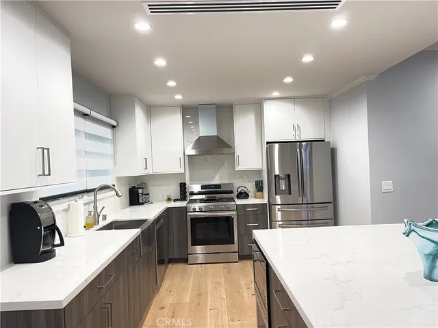 a kitchen with stainless steel appliances granite countertop a sink stove refrigerator and cabinets