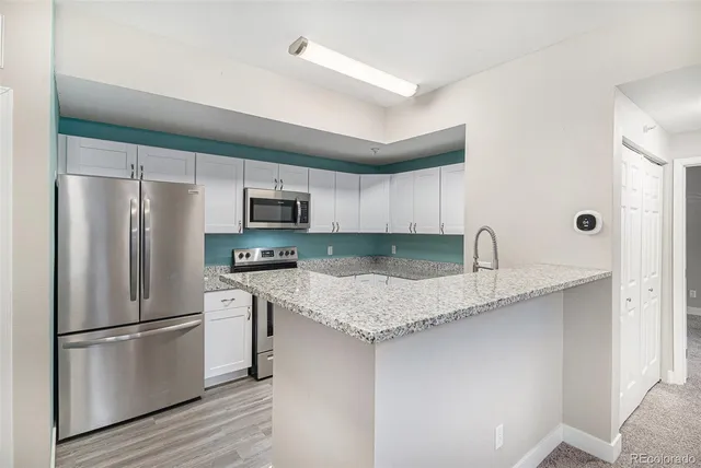 a kitchen with stainless steel appliances granite countertop a refrigerator a sink a stove a microwave and wooden cabinets