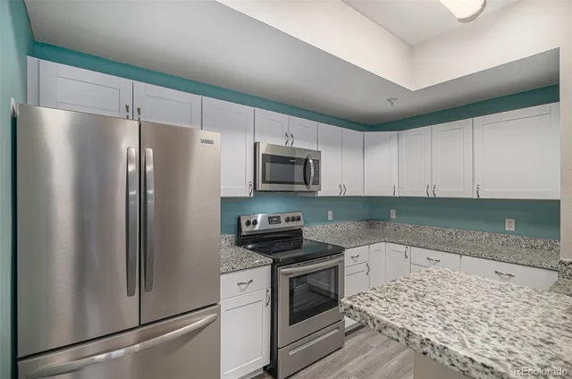 a kitchen with granite countertop a refrigerator stove and microwave