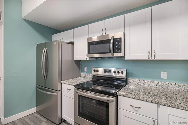 a kitchen with stainless steel appliances granite countertop white cabinets granite counter tops and a wooden floors