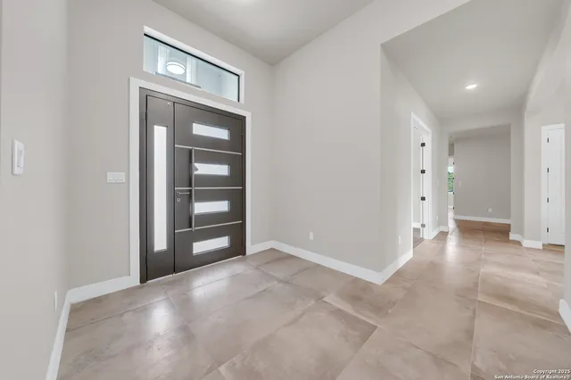 a large white kitchen with granite countertop a large window and a refrigerator
